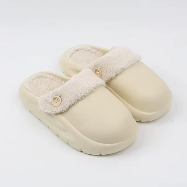 Beige Hausschuhe mit flauschigem Futter und Knopfdetail, rutschfeste Sohle, ideal für Komfort und Wärme im Winter. Perfekte Pantoffeln für Zuhause.