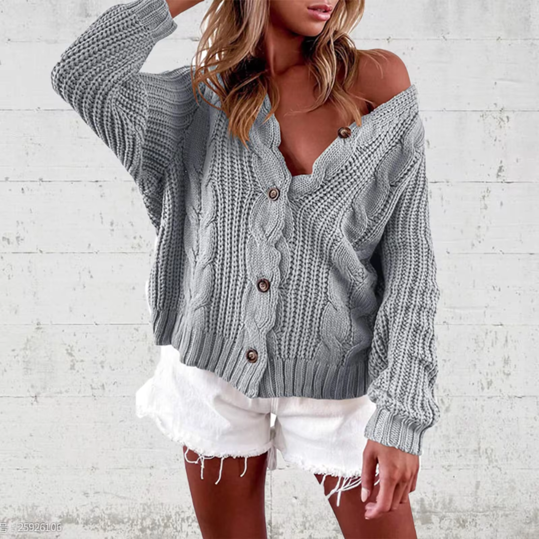Frau in grauem Strickpullover und weißen Shorts vor Betonwand. Modetrend, lässiger Look, Herbstmode, Strickmode, Damenbekleidung.