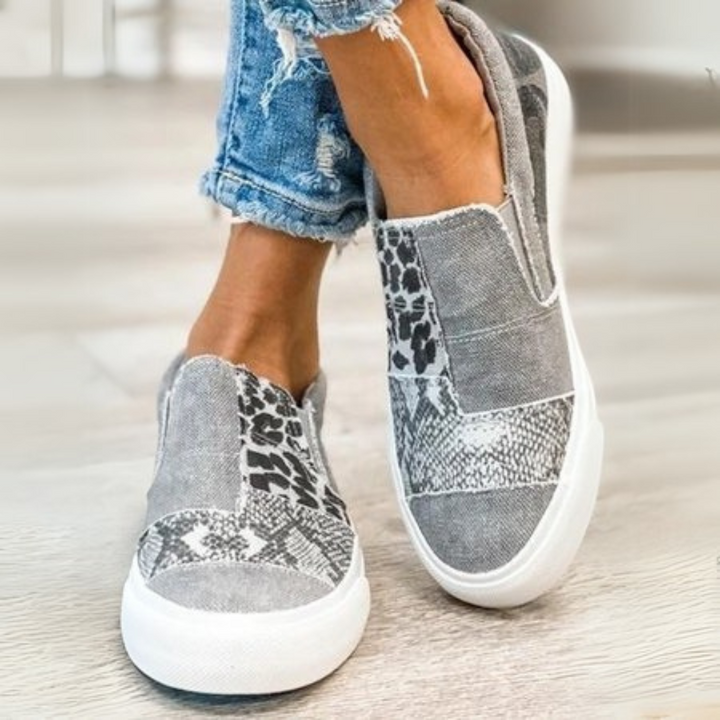 Graue Damen-Sneaker mit Leoparden- und Schlangenprint, getragen zu hochgekrempelten Jeans. Modische Freizeitschuhe, ideal für den Alltag.