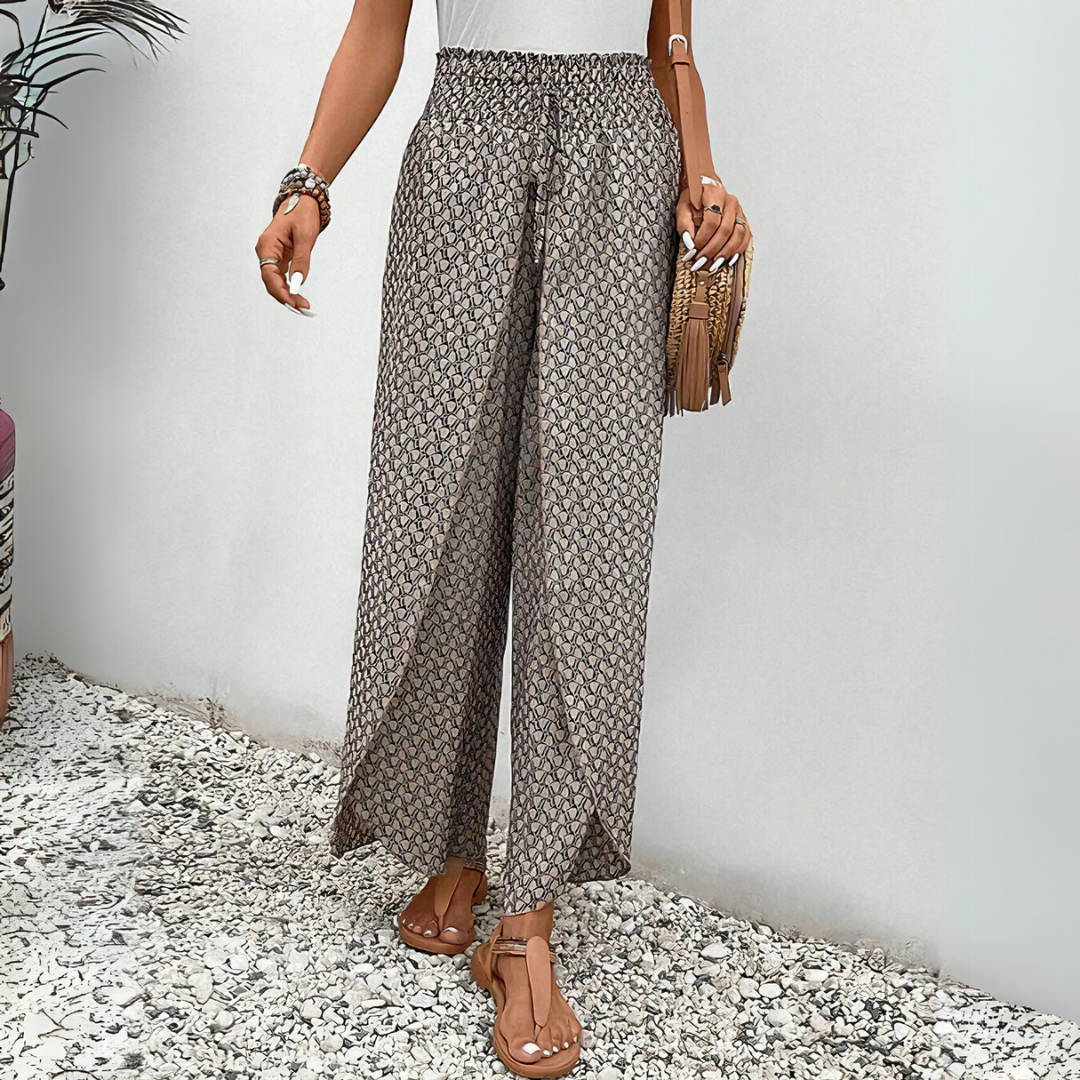 Frau in gemusterten Sommerhosen, Sandalen und mit Fransenhandtasche. Modetrend, Damenbekleidung, lässiger Stil, Sommermode.