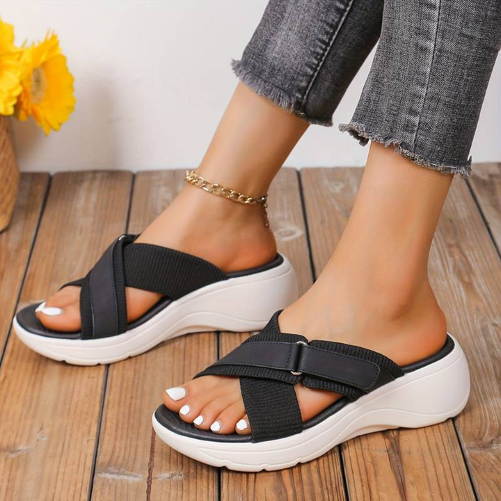 Damen Sandalen mit Keilabsatz, schwarz, bequem, modisch, auf Holzfußboden. Perfekt für Sommermode und Freizeitkleidung.
