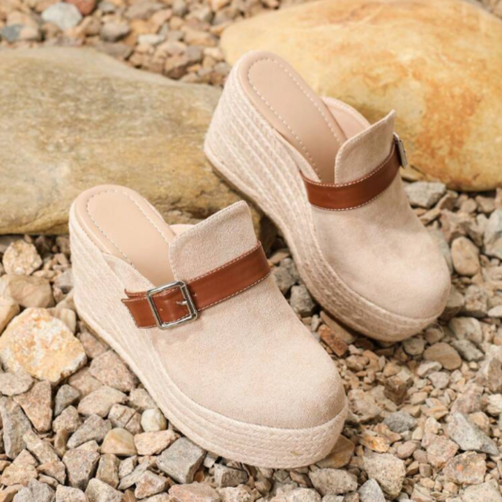 Beige Plateau-Sandalen mit Keilabsatz und braunem Riemen auf Kieselsteinen. Modische Damen-Sommerschuhe, ideal für lässige Outfits.
