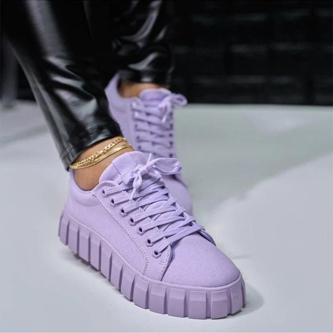 Lila Sneaker mit dicker Sohle, getragen von Person in schwarzer Lederhose. Modische Turnschuhe, trendige Schuhe, Streetwear-Mode.
