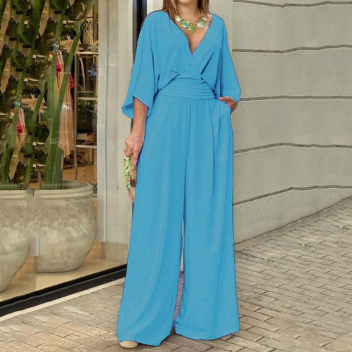 Frau in blauem Jumpsuit vor Geschäft, modisch, elegant, Sommermode, Damenbekleidung, stilvoll, trendig, Accessoires, Stadtbummel.