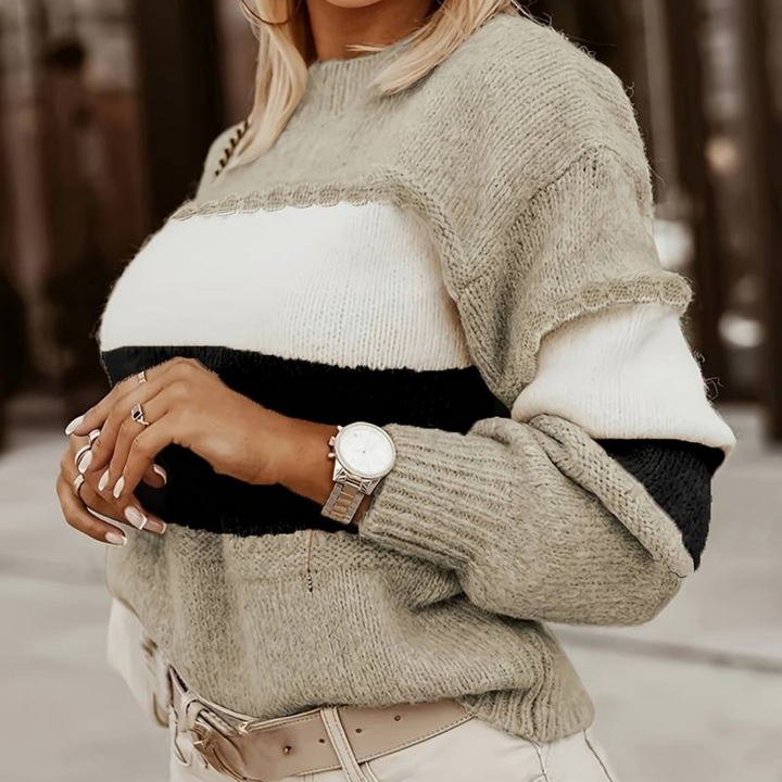 Frau in gestreiftem Strickpullover, beige und schwarz, mit Armbanduhr und beigen Hosen. Modetrend Herbst, stilvolle Damenbekleidung.