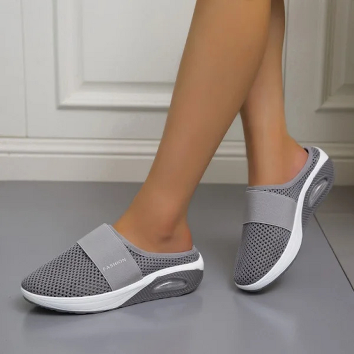 Graue Damen-Sneaker-Slipper mit atmungsaktivem Mesh-Obermaterial und weißer Sohle, ideal für Komfort und Mode im Alltag.