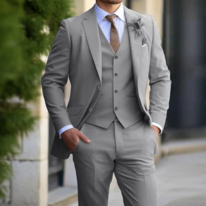 Eleganter Mann im grauen Anzug mit Weste und Krawatte, steht draußen. Businessmode, Herrenanzug, formelle Kleidung, stilvoller Look.