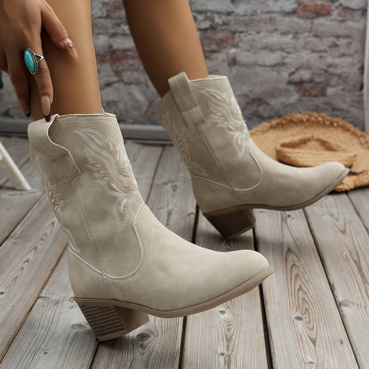 Damen Cowboy Stiefel in Beige mit Stickerei, Holzabsatz, auf Holzboden. Modische Westernstiefel, ideal für Herbstmode und Outdoor-Aktivitäten.