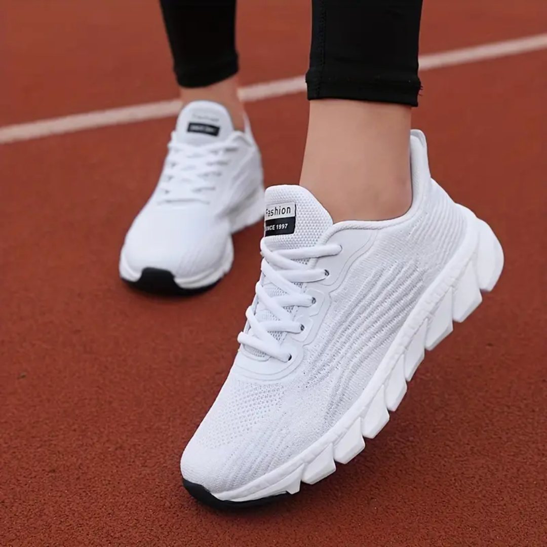 Weiße Sportschuhe auf roter Laufbahn, moderne Laufschuhe, atmungsaktives Design, ideal für Jogging und Fitness, bequeme Passform, Damenmode.