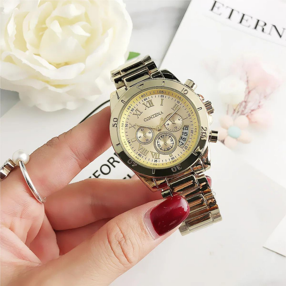 Goldene Damenarmbanduhr mit römischen Ziffern und Chronographen auf silbernem Armband, gehalten von Hand mit rotem Nagellack, neben weißer Blume.