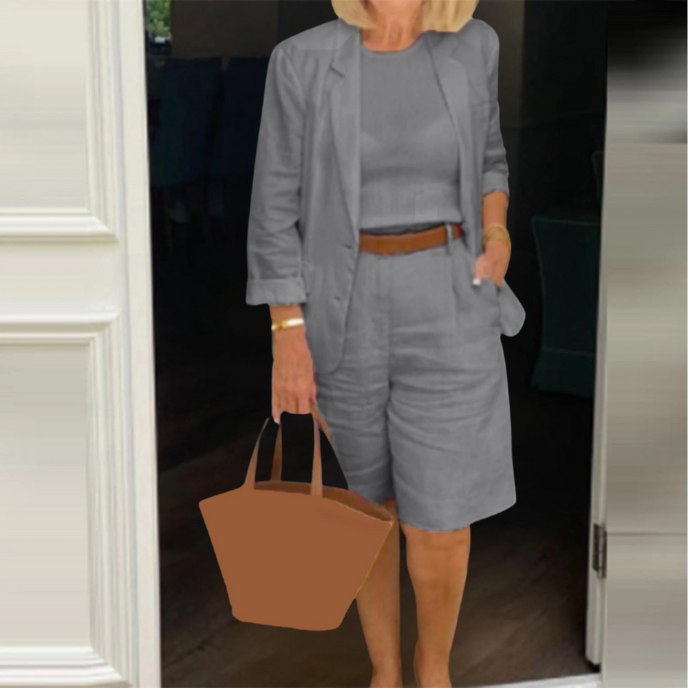 Frau in grauem Sommeranzug mit Shorts und Blazer, hält braune Handtasche. Modetrend, Business-Casual, stilvoller Look für warme Tage.