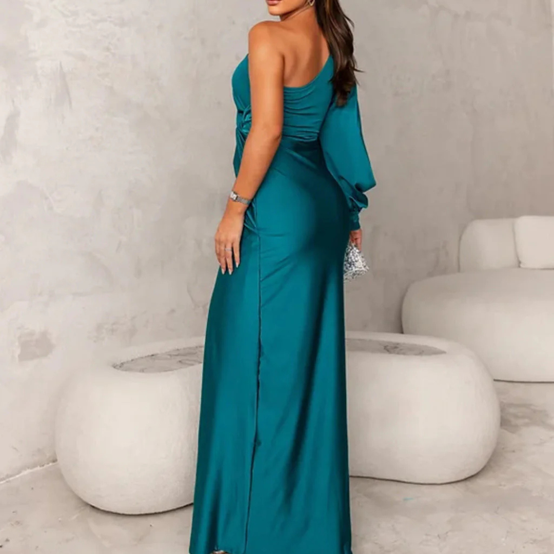 Frau in elegantem, einarmigem, türkisfarbenem Abendkleid posiert in modernem, minimalistischem Raum. Perfekt für Mode, Abendmode, Damenbekleidung.