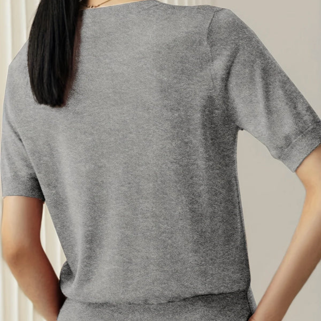 Frau in grauem T-Shirt von hinten, modernes Design, kurze Ärmel, glattes Haar, minimalistische Mode, stilvolle Damenbekleidung.