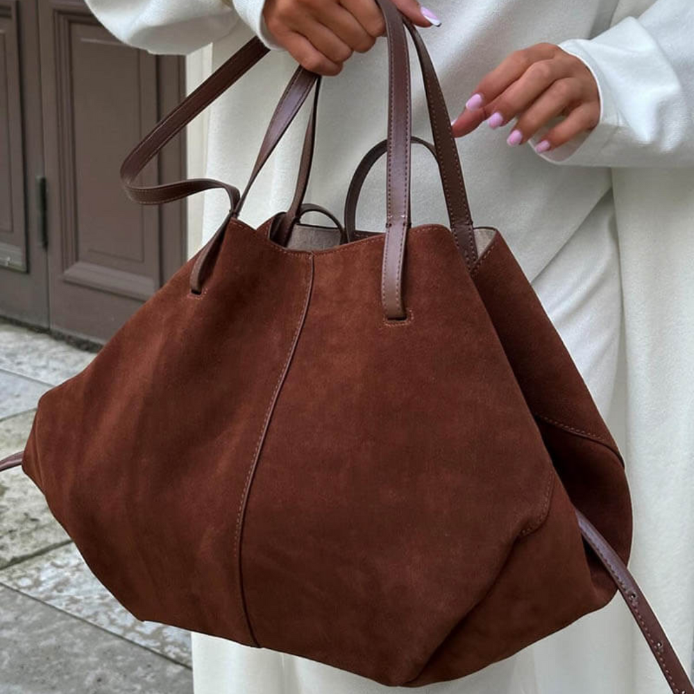 Frau mit großer brauner Wildledertasche, modisches Accessoire, elegante Handtasche, Herbstmode, stilvoller Look, Damenmode, Stadtbummel.