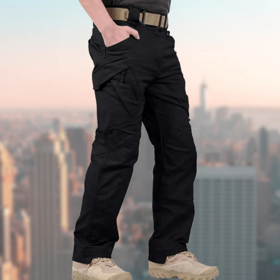 Schwarze taktische Hose für Herren, robust und vielseitig, ideal für Outdoor-Aktivitäten. Hintergrund: Stadtansicht mit Hochhäusern.