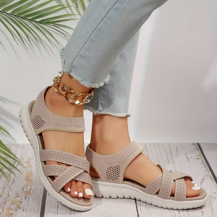 Beige Damen-Sandalen mit Strickdesign und weißer Sohle, getragen mit hellblauen Jeans. Sommermode, bequeme Schuhe, stilvolle Fußbekleidung.