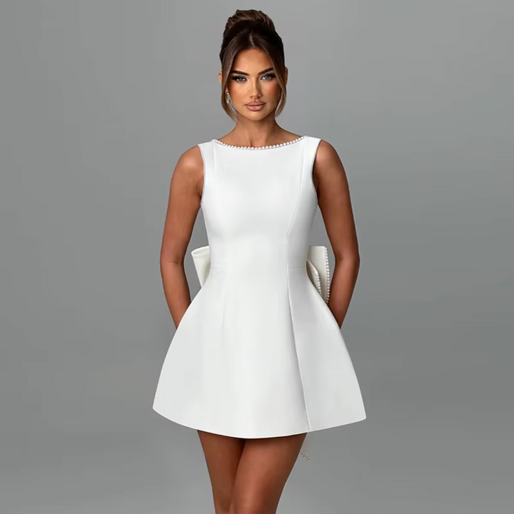 Eine Frau in einem eleganten, weißen Cocktailkleid vor grauem Hintergrund. Mode, Abendkleid, stilvoll, Damenmode, schickes Outfit.
