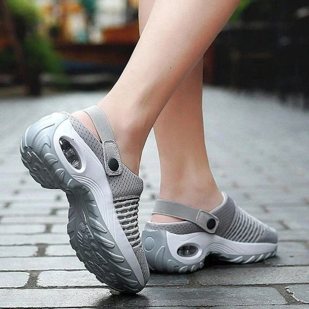 Graue, atmungsaktive Clogs mit rutschfester Sohle auf Kopfsteinpflaster. Bequeme, modische Schuhe für Damen, ideal für Freizeit und Outdoor.