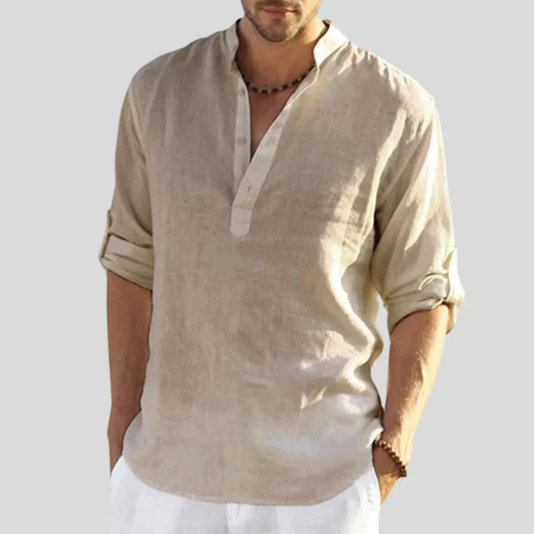 Mann trägt beiges Leinenhemd mit Stehkragen und Knopfleiste, Ärmel hochgekrempelt. Sommermode, lässiger Stil, Herrenbekleidung.