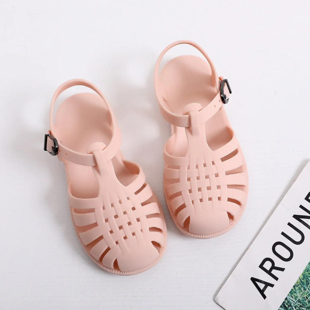 Rosa Sandalen aus Kunststoff mit Riemen und Schnalle auf weißem Hintergrund, modische Sommerschuhe, ideal für Strand und Freizeit.