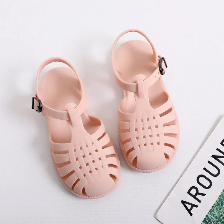 Rosa Sandalen aus Kunststoff mit Riemen und Schnalle auf weißem Hintergrund, modische Sommerschuhe, ideal für Strand und Freizeit.