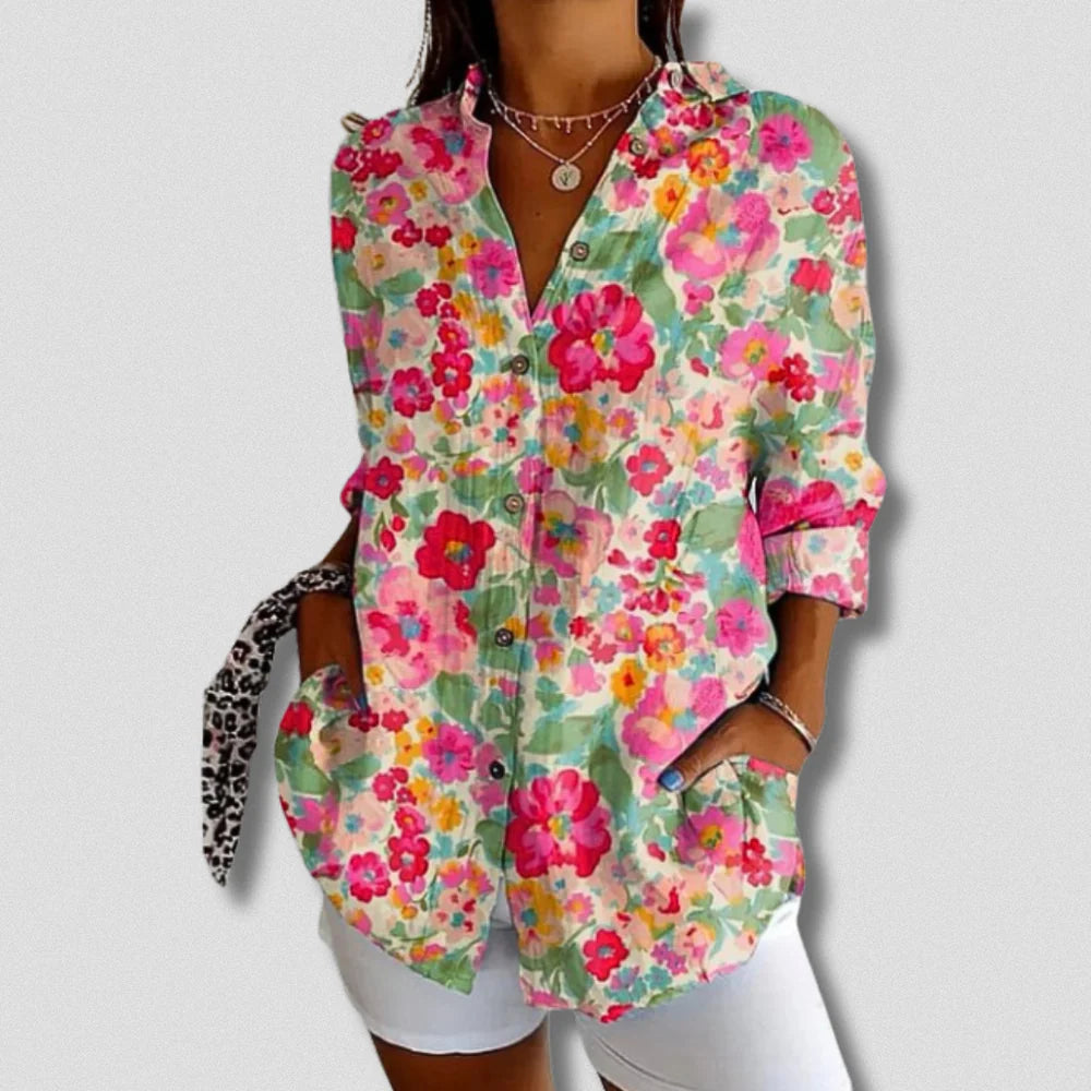 Bunte Damenbluse mit Blumenmuster, langen Ärmeln und Knopfleiste, kombiniert mit weißen Shorts. Modische Sommerkleidung, lässiger Stil.