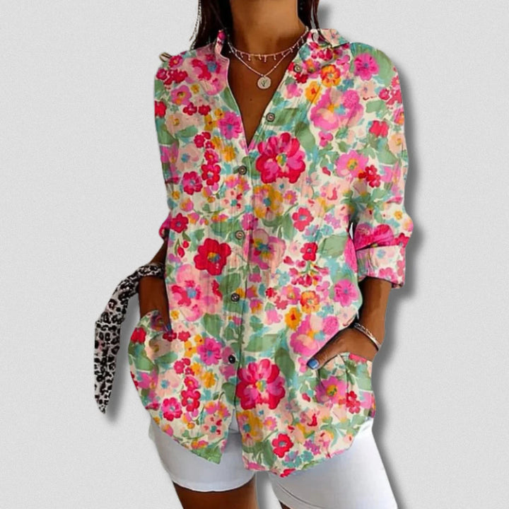 Bunte Damenbluse mit Blumenmuster, langen Ärmeln und Knopfleiste, kombiniert mit weißen Shorts. Modische Sommerkleidung, lässiger Stil.