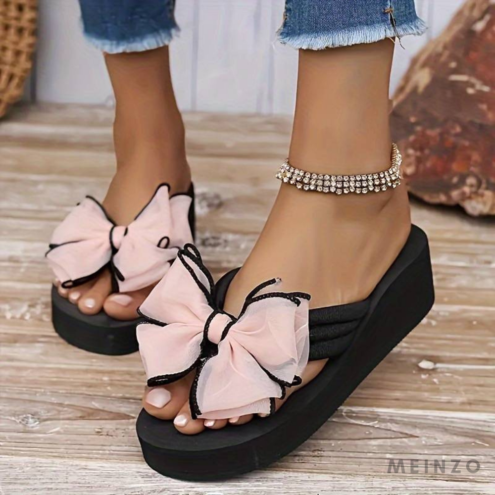Damen Sandalen mit Plateau, rosa Schleifen und Strass-Details, kombiniert mit Jeans. Modische Sommerschuhe, ideal für trendige Outfits.