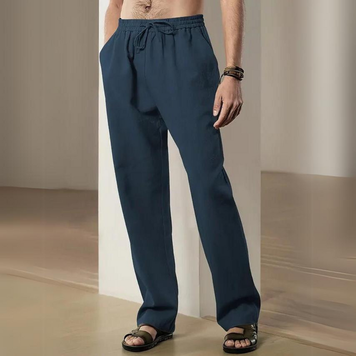Mann trägt dunkelblaue Freizeithose mit Kordelzug, kombiniert mit Sandalen. Bequeme Herrenmode, ideal für lässige Anlässe und Sommeroutfits.