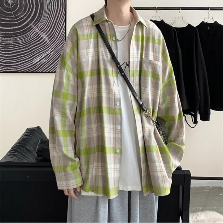 Person in übergroßem kariertem Hemd mit grünen und beigen Streifen, weißem T-Shirt und grauer Hose. Modetrend, lässiger Stil, Herrenmode.