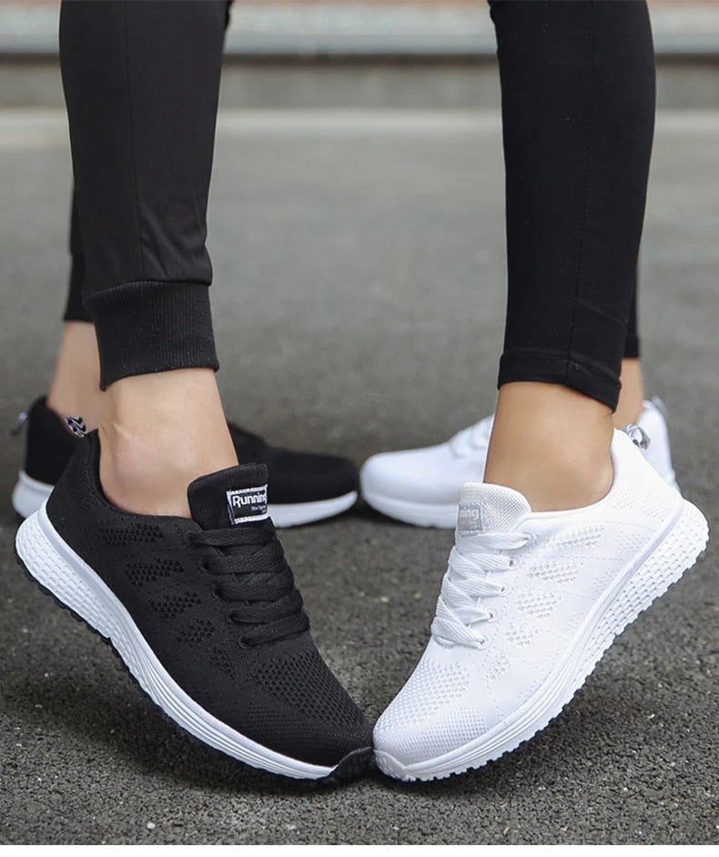 Zwei Paar Sportschuhe, schwarz und weiß, auf Asphalt getragen von Personen in schwarzen Leggings. Bequeme, atmungsaktive Laufschuhe für Damen.