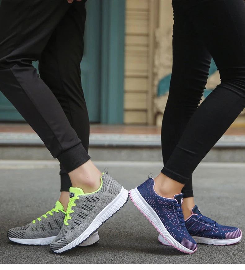Zwei Personen tragen modische Sportschuhe: graue Sneaker mit neongelben Akzenten und blaue Sneaker mit rosa Details. Ideal für Laufen und Freizeit.