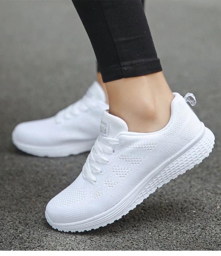 Weiße Damen-Sneaker auf Asphalt, atmungsaktives Mesh-Design, ideal für Laufen und Freizeit, modische Sportschuhe, bequeme Passform.