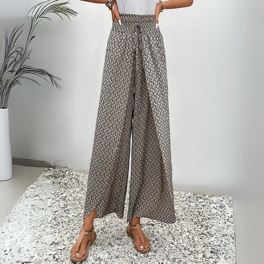 Damenhose mit weitem Bein, geometrischem Muster und elastischem Bund, kombiniert mit Sandalen. Perfekt für Sommermode und Freizeitoutfits.