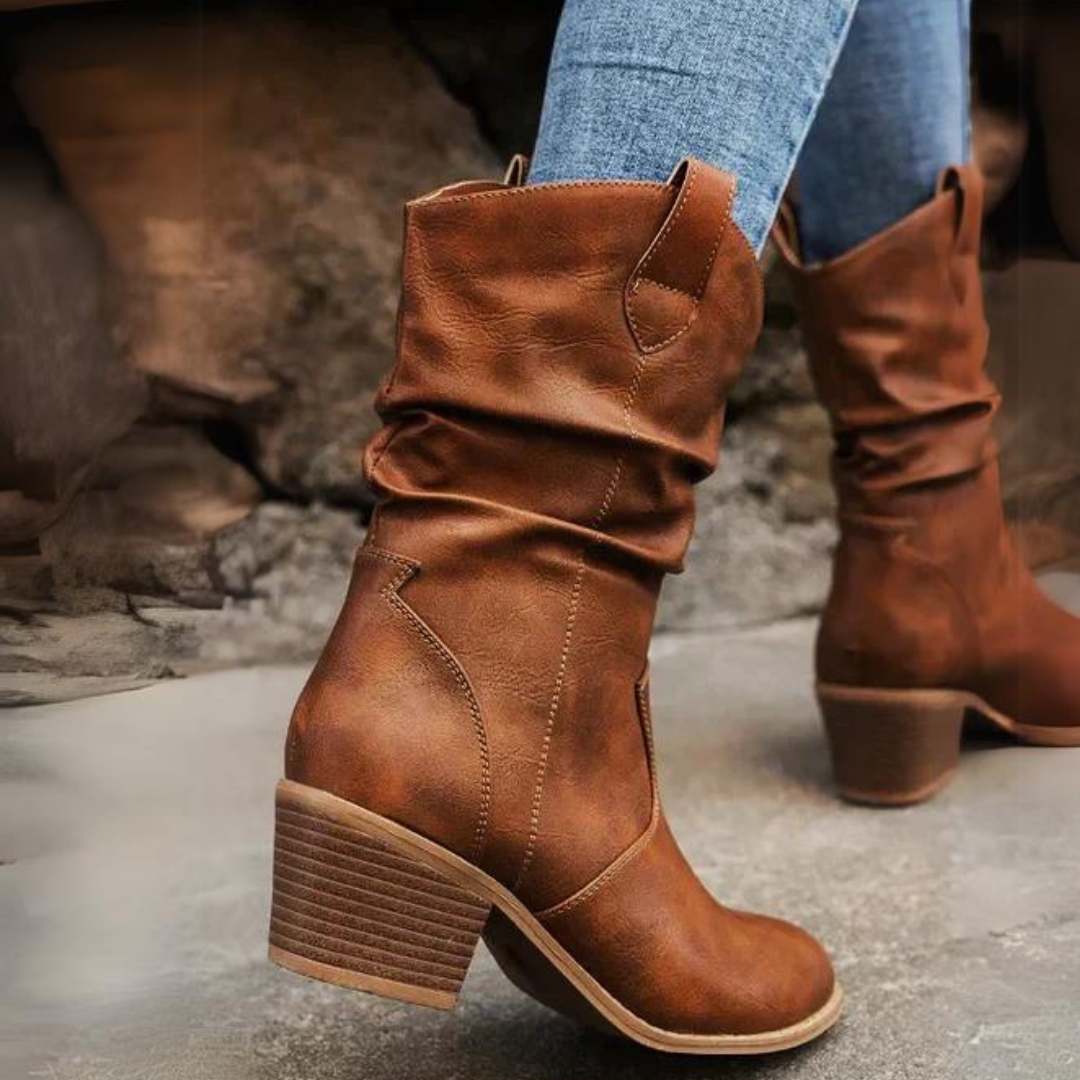 Braune Cowboystiefel aus Leder mit Blockabsatz, getragen von Person in blauer Jeans. Modische Damenstiefel, ideal für Herbstmode und Outdoor-Aktivitäten.