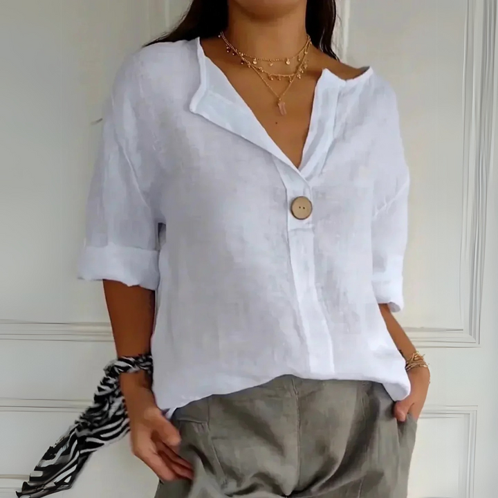 Frau trägt weiße Leinenbluse mit Knopf, kombiniert mit grauer Hose. Modetrend, lässiger Stil, Sommermode, elegantes Design, Damenbekleidung.