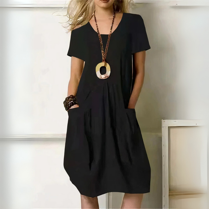 Frau in schwarzem Sommerkleid mit Taschen, trägt auffällige Halskette und Armbänder. Modetrend, lässiger Stil, Damenmode, elegantes Outfit.