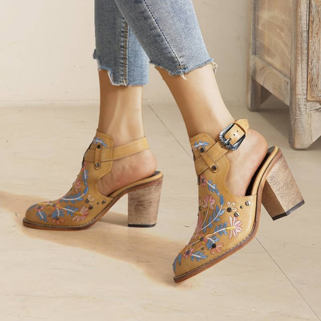 Damen Clogs mit Absatz, gelb, bestickt mit Blumenmuster, getragen mit hochgekrempelten Jeans. Modische Schuhe, trendige Damenmode.