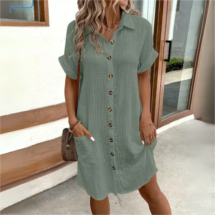 Frau in grünem Hemdkleid mit Knopfleiste und Taschen, lässiger Sommerlook, modische Freizeitkleidung, draußen vor einem modernen Gebäude.