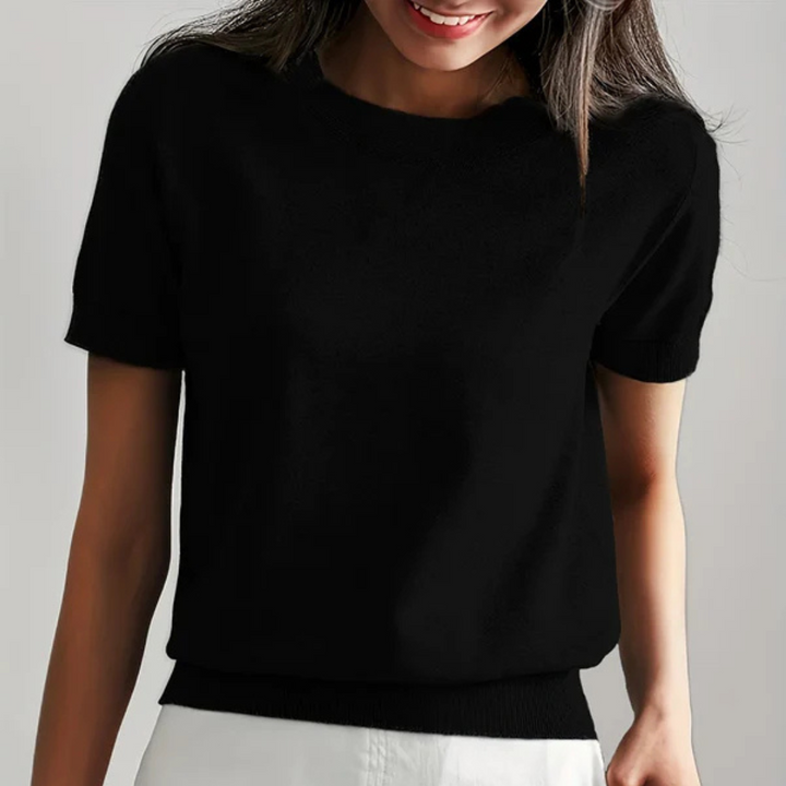 Frau in schwarzem T-Shirt und weißem Rock, lächelnd. Modetrend, Damenbekleidung, lässiger Stil, Sommeroutfit, minimalistisch, elegant.