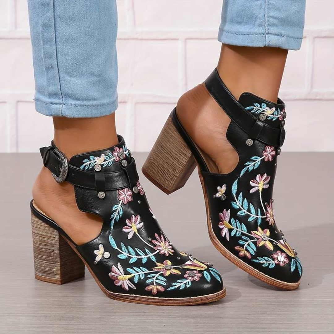 Schwarze Lederstiefeletten mit bunten Blumenstickereien, Blockabsatz und Schnallenverschluss, getragen mit hellblauen Jeans.