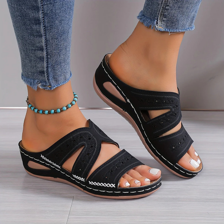 Schwarze Damen-Sandalen mit Keilabsatz, getragen mit Jeans. Modische Sommerschuhe, bequem und stilvoll, ideal für Freizeit und Alltag.