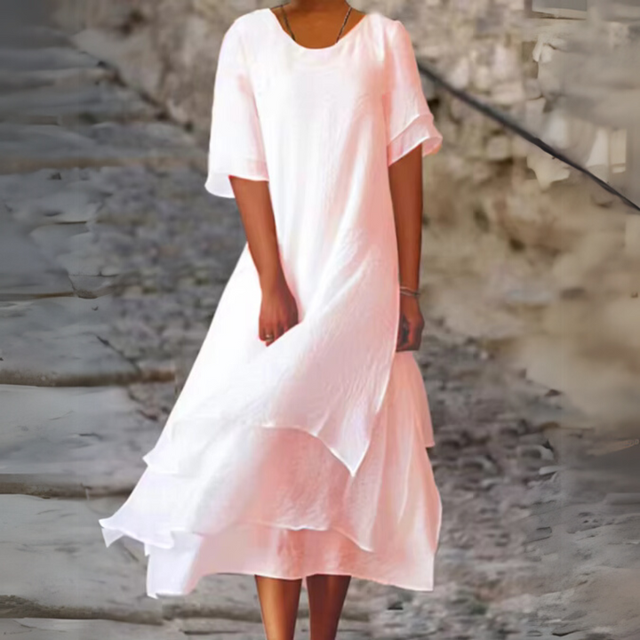 Frau in weißem Sommerkleid auf Kopfsteinpflasterstraße. Luftiges, elegantes Design, ideal für warme Tage. Mode, Damenbekleidung, Sommeroutfit.