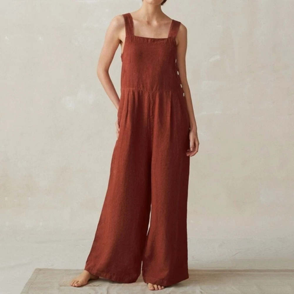 Frau trägt roten Leinen-Jumpsuit mit breiten Trägern, lockerem Schnitt und weitem Bein. Modetrend, nachhaltige Damenbekleidung, lässiger Stil.