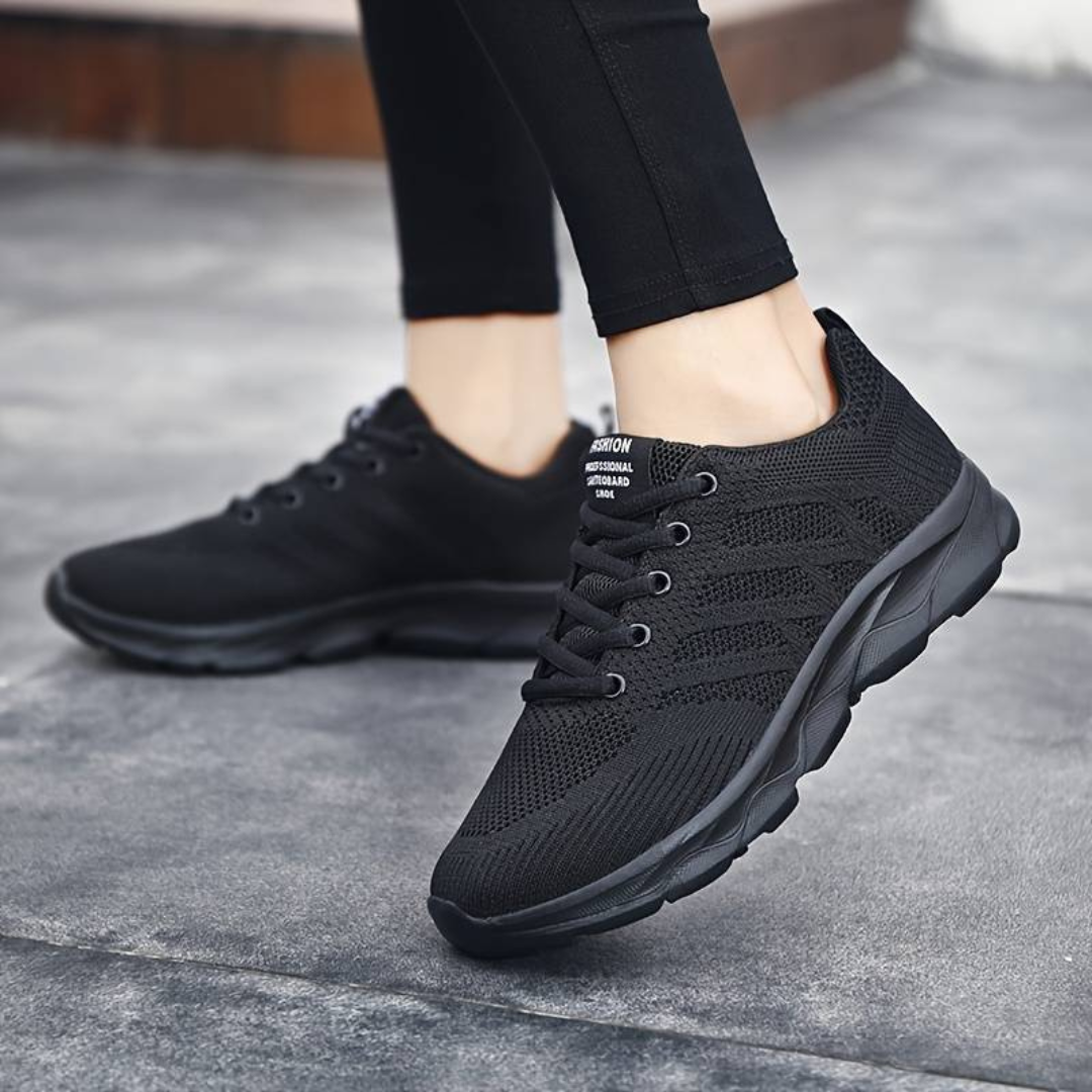 Schwarze Damen-Sneaker aus atmungsaktivem Mesh, ideal für Laufen und Freizeit. Bequeme Sportschuhe mit rutschfester Sohle auf grauem Boden.
