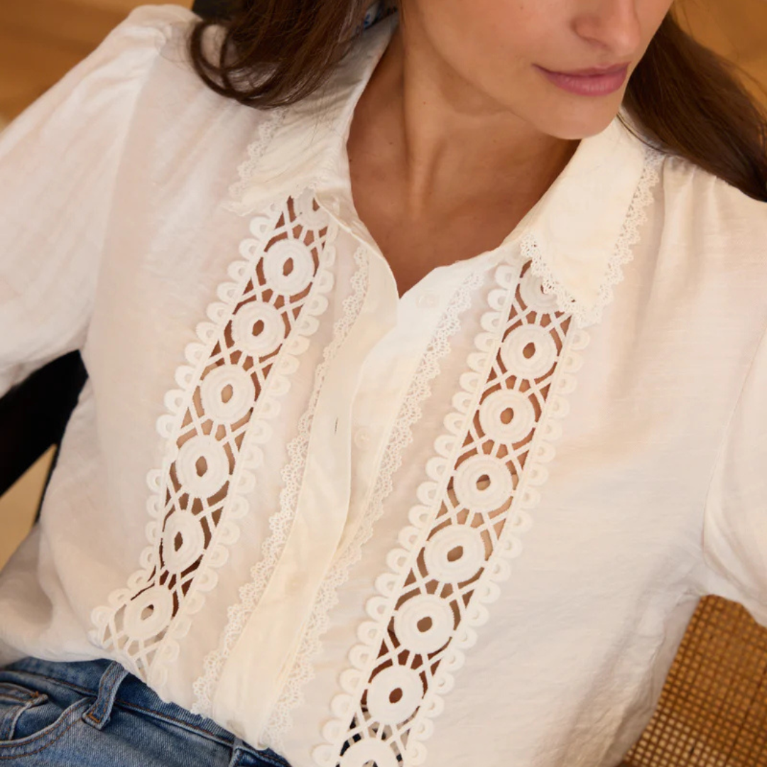 Weiße Bluse mit Spitzenmuster, getragen von Frau. Elegante Damenmode, stilvolles Design, ideal für Büro und Freizeit. Hochwertige Baumwolle.