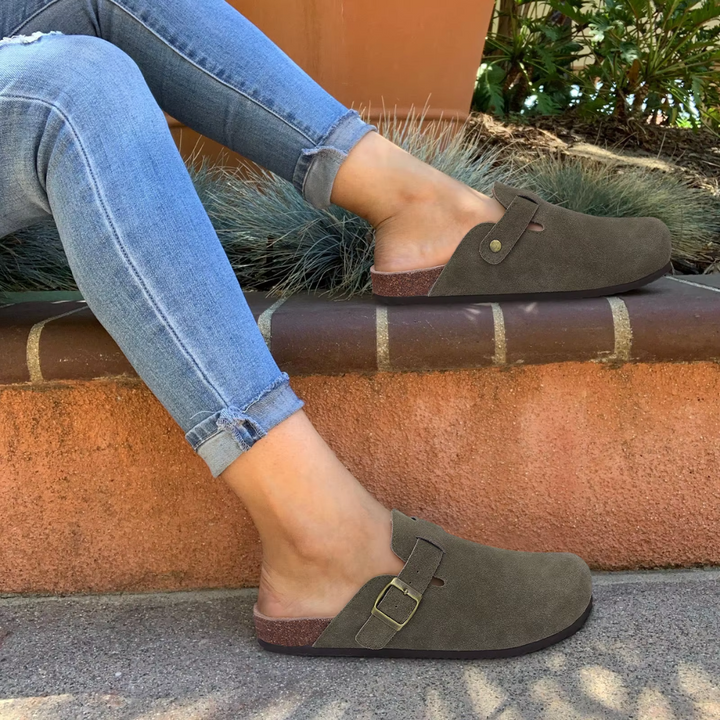 Jeans und braune Clogs auf einer Mauer; bequeme Damen-Schuhe, Freizeitlook, modische Fußbekleidung, ideal für Herbst und Frühling.