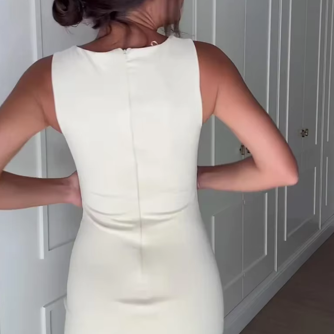 Frau in elegantem, ärmellosem weißen Kleid vor einem Kleiderschrank. Mode, Damenbekleidung, elegantes Outfit, stilvolles Design.