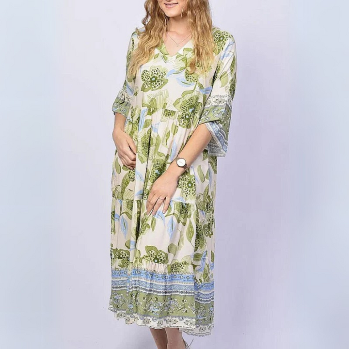 Frau in langem, geblümtem Kleid mit V-Ausschnitt und 3/4-Ärmeln, trägt Armbanduhr. Sommermode, Damenkleid, florales Muster.