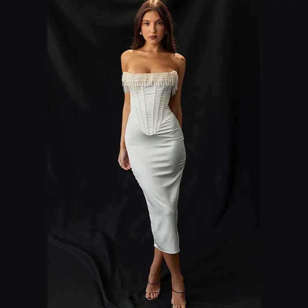 Frau in elegantem, schulterfreiem weißen Kleid mit Korsett und Fransen, posiert vor schwarzem Hintergrund. Abendmode, Damenkleid, Modefotografie.